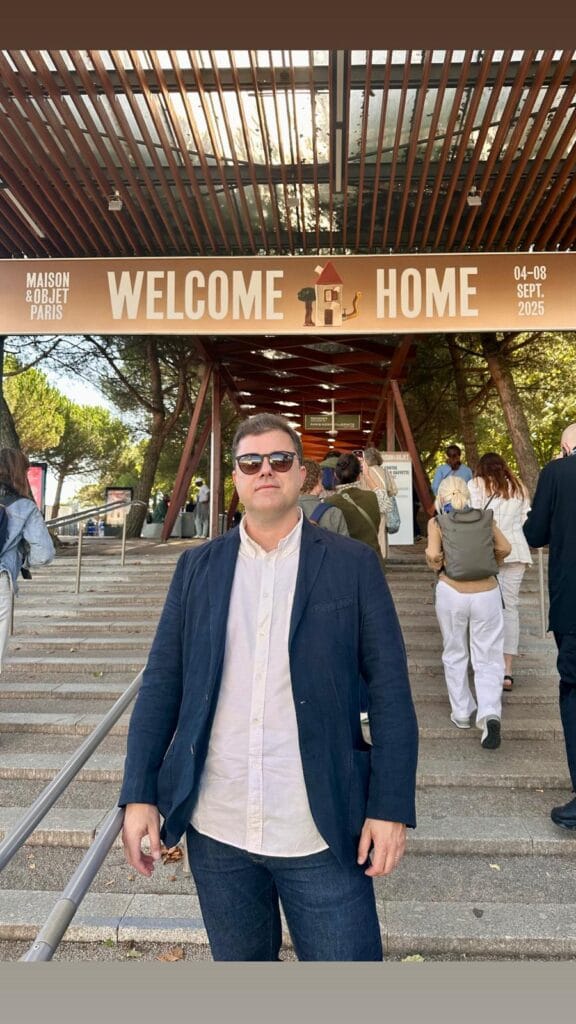 Homem em trajes esporte fino e óculos escuros na entrada do evento Maison e Objet Paris sob o painel Welcome Home.