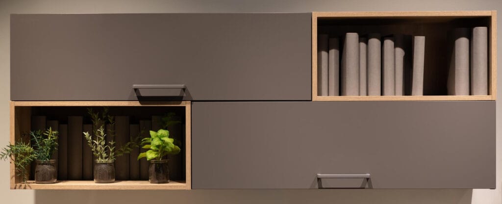 Móvel de parede modular com armários suspensos cinza e nichos de madeira com livros e pequenos vasos de plantas para armazenamento inteligente.
