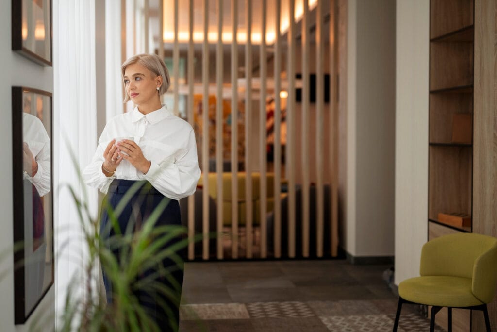 Mulher em ambiente elegante com design de luxo contemporaneo, divisoria de madeira e acabamentos discretos.